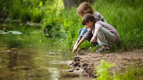 Kinder sitzen am Ufer des Schweriner Sees